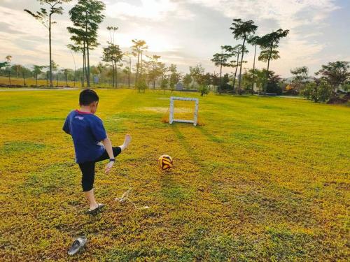 a young boy playing with a soccer ball in a field at Spring Fields Homestay by Sizma in Semenyih