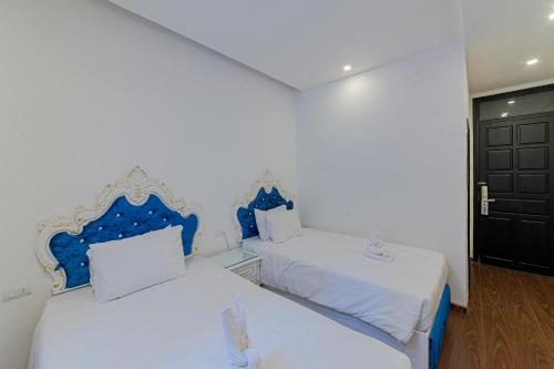 a bedroom with two beds with blue and white pillows at Nostalgia Hotel and Spa in Hoi An