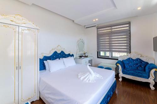 a bedroom with a blue and white bed and two chairs at Nostalgia Hotel and Spa in Hoi An