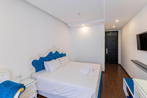 a bedroom with a blue and white bed and a tv at Nostalgia Hotel and Spa in Hoi An