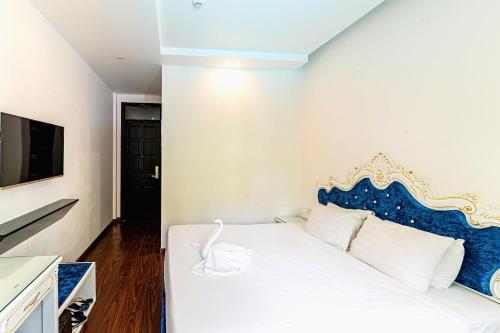a bedroom with a white bed with a blue headboard at Nostalgia Hotel and Spa in Hoi An