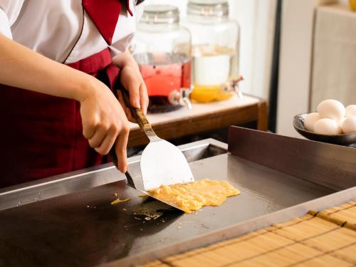 a person using a spatula to cut a piece of food at Hotel Gracery Kyoto Sanjo in Kyoto