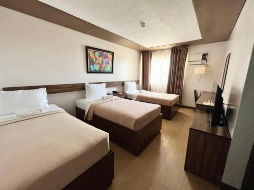 a hotel room with two beds and a television at Leope Hotel in Cebu City