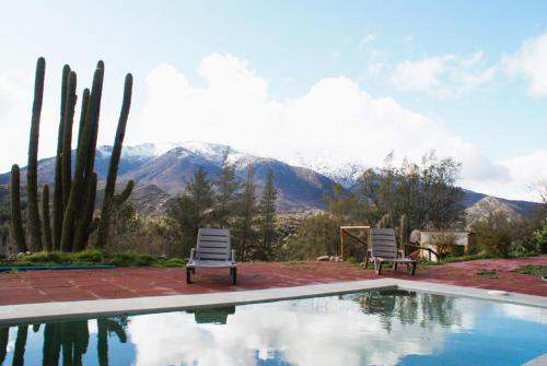 een zwembad met twee stoelen en bergen op de achtergrond bij Ladera Encanto in Caleu