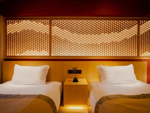 two beds in a hotel room with a window at Hotel Gracery Kyoto Sanjo in Kyoto