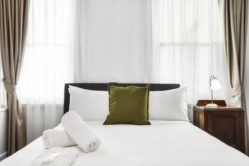 een bed met witte lakens en groene kussens bij Grand View Hotel in Wentworth Falls