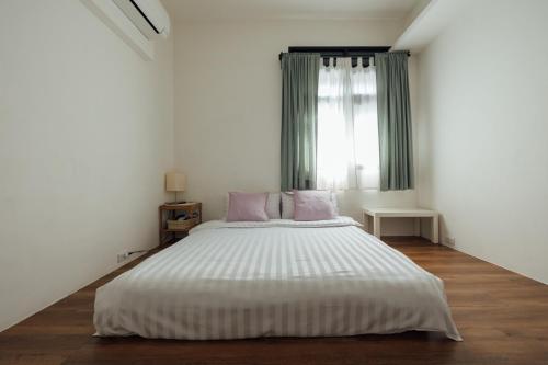 a white bedroom with a large bed with pink pillows at 5963 Turn Right B&B in Jiaoxi