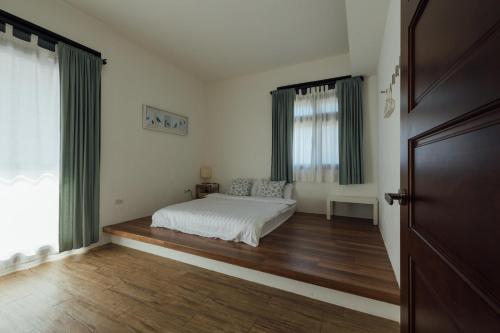 a bedroom with a bed and a wooden floor at 5963 Turn Right B&B in Jiaoxi