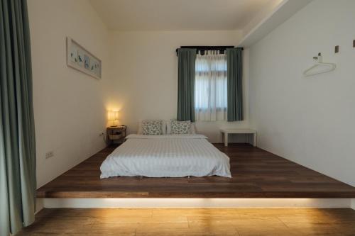 a bedroom with a white bed and a window at 5963 Turn Right B&B in Jiaoxi