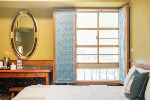 a bedroom with a bed and a mirror and a window at 翠安儂風旅 in Taitung City