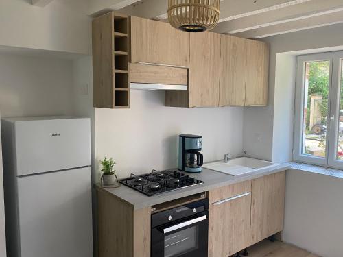 a kitchen with a white refrigerator and a stove top oven at Le gîte des Grivots 