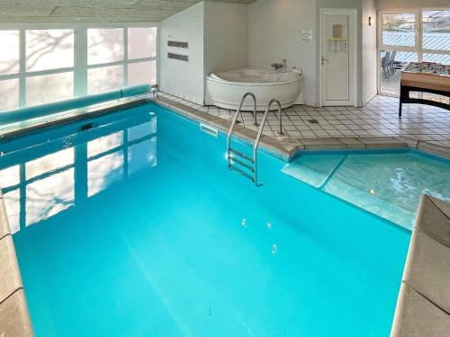 a large pool with a tub in a bathroom with a toilet and a bath tub at 10 person holiday home in Glesborg in Fjellerup Strand