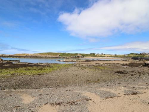 a beach with a body of water and a cloudy sky at Ger Y Mor in Cemaes Bay