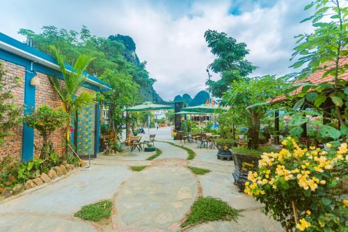 a walkway with tables and chairs and trees at Phong Nha Green Homestay in Phong Nha