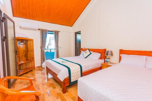 a bedroom with two beds and a chair at Phong Nha Green Homestay in Phong Nha