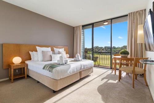 a bedroom with a bed and a desk and a balcony at Fairway Views – Moonah Apartment 23 in Fingal