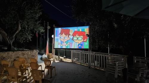 a large screen with cartoons on it at night at Village Valle D'Oro ApartHotel in San Menaio