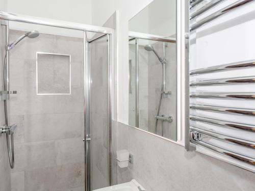 a bathroom with a shower and a toilet and a mirror at Pogles Wood Cottage in Skipton