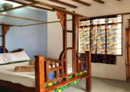 a bedroom with a wooden bed and a window at Magharibi House in Nungwi