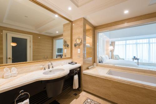 a bathroom with a large tub and a large mirror at Qingdao Jinshi International Hotel in Qingdao