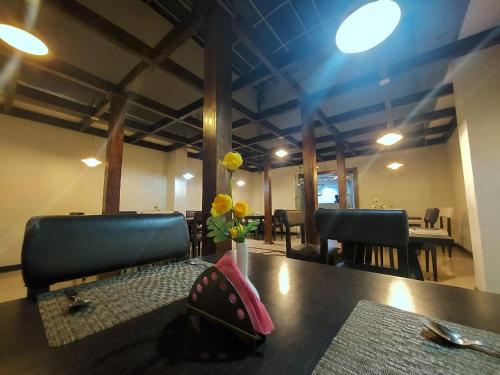 a dining room table with a vase with flowers on it at Orbit Hotel - Bagdogra in Bāghdogra