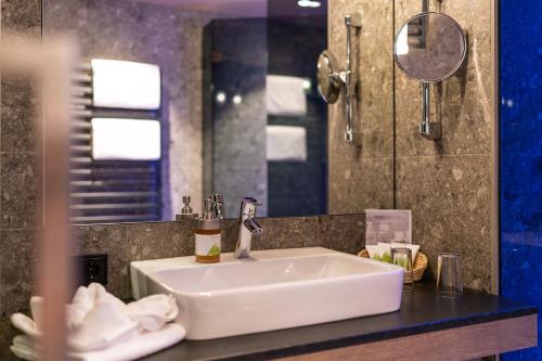 a bathroom with a white sink and a mirror at Dolomiten Residenz - Sporthotel Sillian in Sillian
