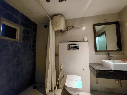 a bathroom with a toilet and a sink and a mirror at Orbit Hotel - Bagdogra in Bāghdogra