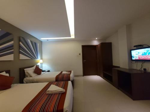 a hotel room with two beds and a flat screen tv at Orbit Hotel - Bagdogra in Bāghdogra