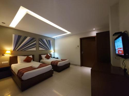 a hotel room with two beds and a flat screen tv at Orbit Hotel - Bagdogra in Bāghdogra