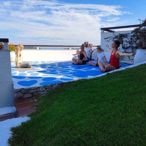a group of people sitting on a blue floor next to the beach at VILLA ALEXIS in Megali Ammos