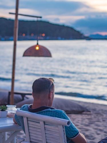a man sitting in a chair watching the ocean at Sea Valley Resort in Lipa Noi