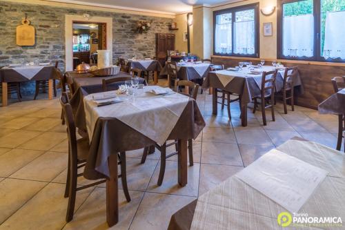 un ristorante con tavoli e sedie in una stanza di Locanda Aquila Bianca a Valprato Soana