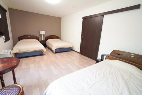 a bedroom with two beds and a desk and a table at 桔恭(KIKYO) in Otaru