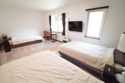 a bedroom with two beds and a flat screen tv at 桔恭(KIKYO) in Otaru