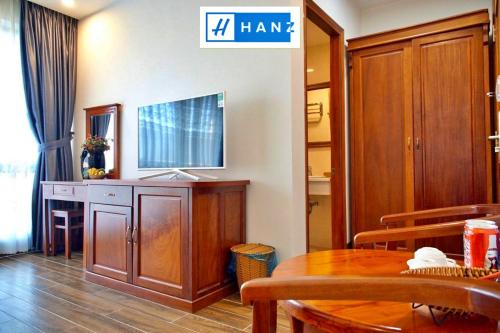 a living room with a table and a tv on a wall at HANZ Sang Sang Hotel in Phu Quoc
