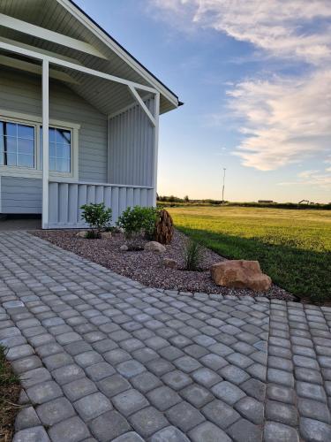 a house with a brick driveway next to a field at Atostogų pieva in Žibininkai