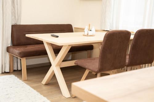 a wooden table with two chairs and a remote control on it at Rosspointnerhof in Haus im Ennstal