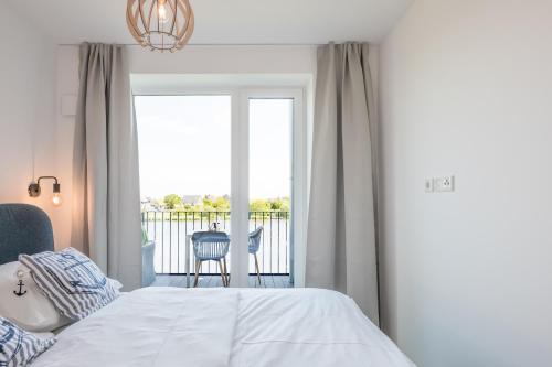 - une chambre avec un lit et une vue sur un balcon dans l'établissement Apartment N14 direkt am Nordseedeich mit Blick auf den See, à Nordstrand