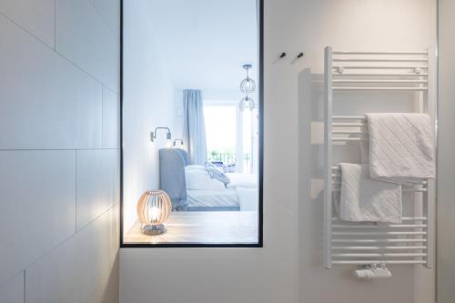 La salle de bains est pourvue d'un miroir et d'une chaise. dans l'établissement Apartment N14 direkt am Nordseedeich mit Blick auf den See, à Nordstrand