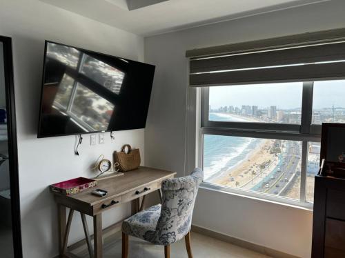 a desk and chair in a room with a view of the beach at Luxury condo en Malecón, Alberca Infinity & Jacuzzi in Mazatlán