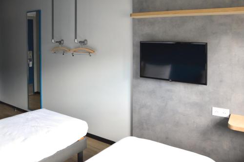 a room with two beds and a flat screen tv at Hotel Ibis Budget Fecamp in Fécamp