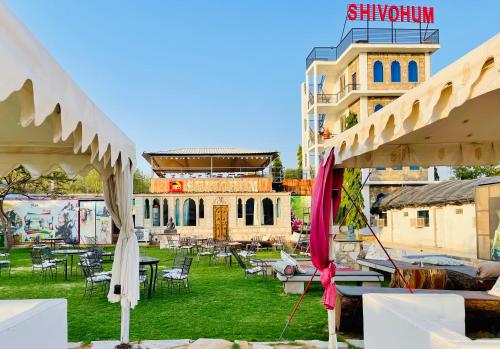 a building with tables and umbrellas in a yard at Shivohum Adventure Retreat in Sāmod