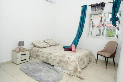 a bedroom with a bed and a chair and a window at Belle demeure spacieuse in Mamoudzou