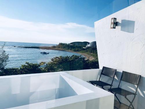 a balcony with two chairs and a view of the ocean at Whose Home Inn in Checheng