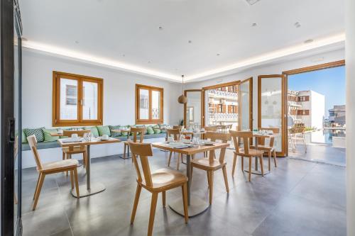 a dining room with tables and chairs and windows at Olia Green Residence in Skopelos Town