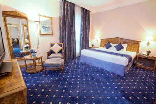 a hotel room with a large bed and a chair at Capitol Hotel Jumeirah Dubai in Dubai