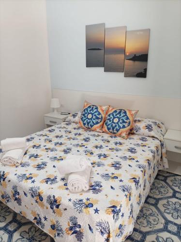 1 dormitorio con cama con colcha y almohadas de flores en b&b Luisa, en Marina di Camerota