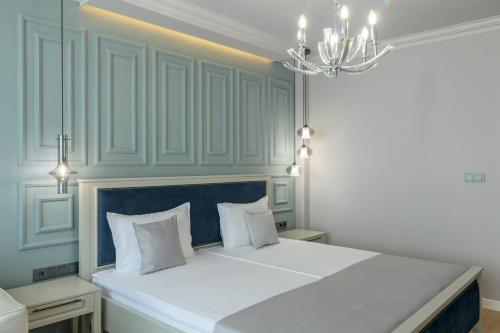 a large white bed in a room with a chandelier at Aquamarine - Beach & SPA Hotel- All inclusive in Kranevo