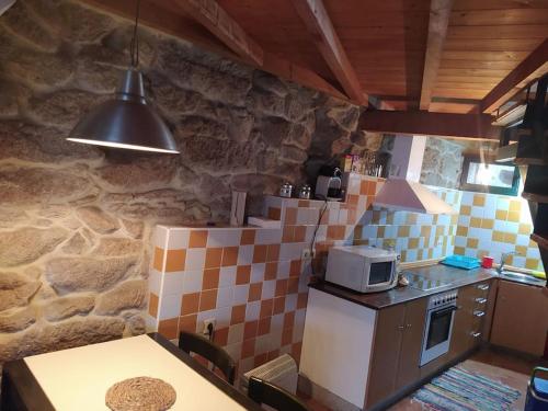 a kitchen with a stove and a microwave at Casa da Vilaboa, Allariz in Allariz