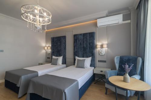 a hotel room with two beds and a table and a chandelier at Aquamarine - Beach & SPA Hotel- All inclusive in Kranevo